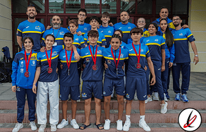 Campeones infantiles de baloncesto con medallas y entrenador en fondo de edificio, vestuarios azules y camisetas deportivas, celebrando victoria en torneo escolar en Lanzarote.