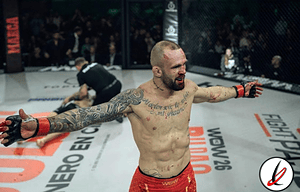 Atleta de artes marciales en el octágono, celebrando victoria tras la pelea, con brazos extendidos y rostro de satisfacción.