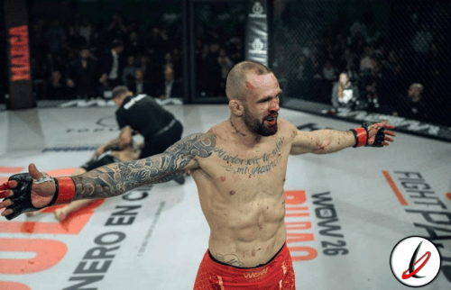 Atleta de artes marciales en el octágono, celebrando victoria tras la pelea, con brazos extendidos y rostro de satisfacción.