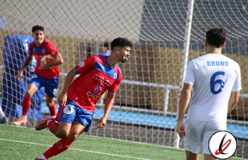 1. Jugador de fútbol celebrando un gol en un partido, con estadio y portería de fondo, vistiendo camiseta roja y azul.