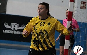 1. Jugadora de balonmano en acción, con camiseta amarilla número 97, en juego en un partido en interiores, con fondo de pista y árbitros.