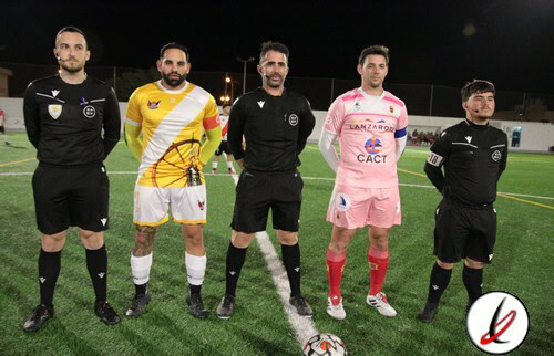 1. Cinco árbitros y dos jugadores en el césped de un campo de fútbol durante una noche de partido.