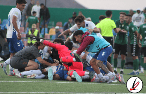Un grupo de jugadores de fútbol en una pelea entre ambos equipos en el campo durante un partido. Hay jugadores en el suelo y otros tratando de separar la pelea, en un ambiente de competencia deportiva.