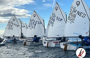 1. Velas de vela ligera en el agua con deportistas navegando bajo un cielo nublado, en un día brillante, en Lanzarote, durante una competición de vela en el mar.