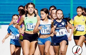 Corredoras en una competición atlética en un estadio, portando ropa deportiva y números de carrera, destacando la concentración y esfuerzo en la pista de Lanzarote Deportiva.