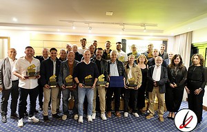 1. Grupo de personas en un evento, algunas sosteniendo trofeos, en una sala con fondo de pantalla y logotipo de Lanzarote Deportiva, en celebración o reconocimiento.