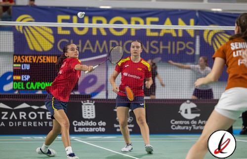 1. Jugadoras de bádminton en acción durante un partido en Lanzarote, con fondo de cartel de UEFA European Championships y público en las gradas.