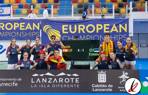 Jugadoras de balonmano del equipo nacional español en la pista durante un partido de campeonato europeo, con pancarta y logo del campeonato visible en el fondo.