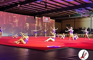 1. Grupos de gimnastas realizando una rutina en una competición en interiores, usando trajes morados y formando diferentes posiciones en el tapiz rojo.