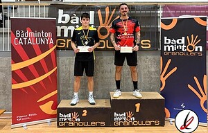 1. Dos jugadores de bádminton en el podio de una competición, uno en primer lugar y otro en segundo, con medallas y certificados, en una instalación deportiva cubierta.
