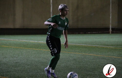 Una jugadora en un campo de fútbol, preparándose para chutar el balón durante un entrenamiento indoor en Lanzarote Deportiva.