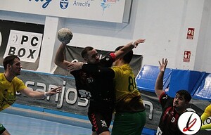 1. Jugador de balonmano lanzando el balón en un partido en el pabellón de Lanzarote, con rivales y espectadores en el fondo.