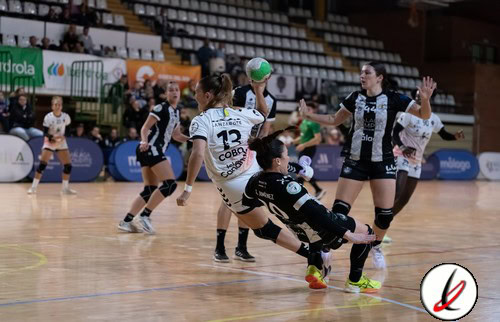 Jugadoras de balonmano en acción durante un partido en un pabellón deportivo.