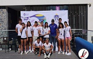 1. Equipo femenino de voleibol de Lanzarote posando junto a su entrenador en un evento deportivo.