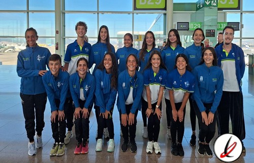 Atletas de fútbol sala en aeropuerto de Lanzarote, equipo femenino en uniforme azul posando para la foto.