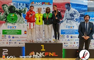 1. Cuatro atletas en podio de judo con medallas, en una ceremonia de premios, acompañados por un juez, en un evento deportivo en Tenerife.