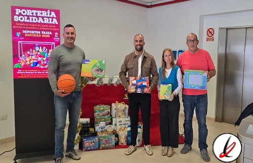 Jóvenes donando regalos en un acto solidario en LanzaroteDeportiva, con una mesa de regalos y un cartel de "Portería Solidaria" en un entorno interior con ascensor y paredes blancas.