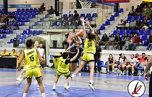 - Jugadoras de baloncesto en acción durante un partido en una cancha cubierta de un pabellón deportivo.