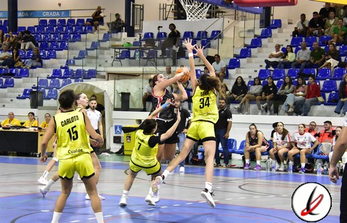 - Jugadoras de baloncesto en acción durante un partido en una cancha cubierta de un pabellón deportivo.