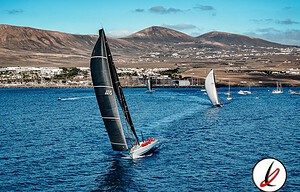 Vela en Lanzarote, deporte náutico en el mar con veleros grandes en agua azul, montañas al fondo y cielo despejado, en un día soleado y ventoso.