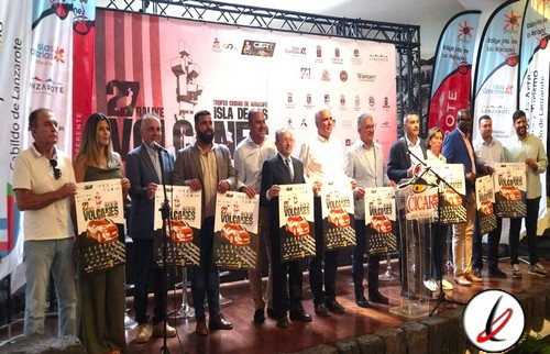 1. Grupo de personas en un escenario con fondos de eventos deportivos y banderas, sosteniendo carteles promocionales en un acto oficial.