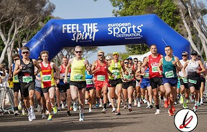 Corredores participando en una maratón en Lanzarote, con un arco de salida con las palabras "Feel the Spirit" y "European Sports Destination" en un día soleado.