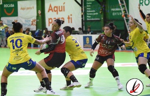 Líderes del partido de balonmano en Lanzarote con jugadoras en acción, algunas en defensa y otras en ataque durante un intenso encuentro en el pabellón deportivo.
