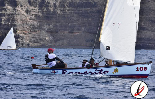 Remeros en un velero durante una regata en el mar con fondo de acantilados, en Lanzarote, promoviendo deportes náuticos y actividades acuáticas en la isla.