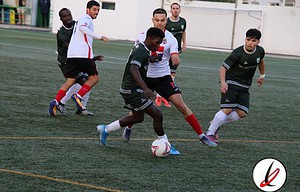 1. Jugadores de fútbol en acción durante un partido en el campo de Lanzarote Deportiva, con jugadores en movimiento y en lucha por el balón en un encuentro juvenil o local.