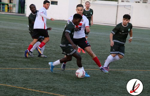 1. Jugadores de fútbol en acción durante un partido en el campo de Lanzarote Deportiva, con jugadores en movimiento y en lucha por el balón en un encuentro juvenil o local.