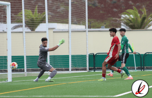 1. Portero en acción deteniendo un disparo durante un partido de fútbol en césped artificial en Lanzarote.