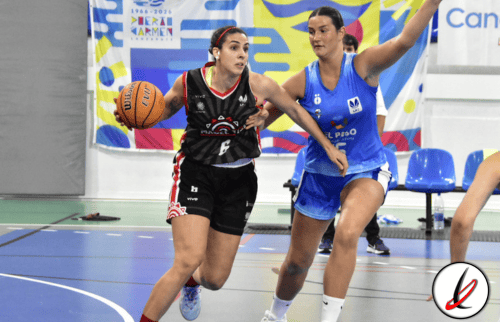 1. Jugadora de baloncesto en acción durante un partido en una cancha cubierta, con otra jugadora defensora y público de fondo.