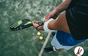 1. Jugador de pádel sosteniendo una pala en pista de césped artificial, preparado para golpear la pelota.