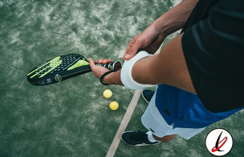 1. Jugador de pádel sosteniendo una pala en pista de césped artificial, preparado para golpear la pelota.