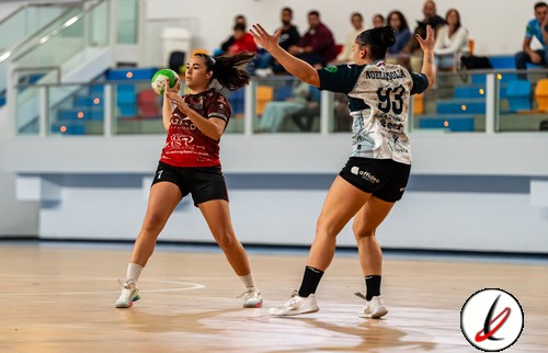 Una jugadora de balonmano en acción en un pabellón deportivo, con otra defendiendo, en un partido en Lanzarote Deportivo.