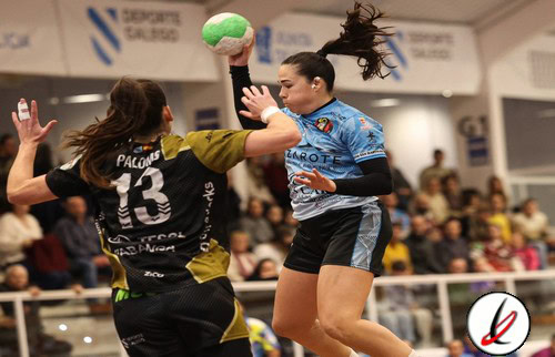 1. Jugadora de balonmano en acción, saltando para lanzar en partido femenino en interiores, con público en las gradas y anuncios publicitarios en el fondo.