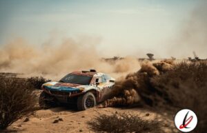 - Un coche de rally en plena carrera en un entorno desértico, levantando polvo y tierra mientras atraviesa el terreno accidentado.