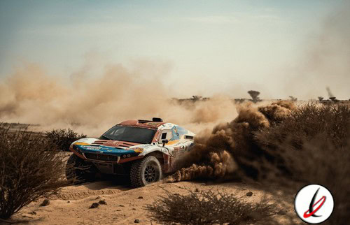 - Un coche de rally en plena carrera en un entorno desértico, levantando polvo y tierra mientras atraviesa el terreno accidentado.