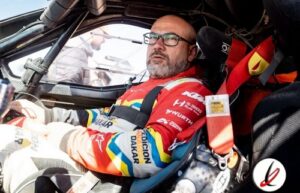 Piloto de carreras en coche de carreras en la cabina, listo para la competencia, con casco y equipo de seguridad, en un entorno de pista de velocidad.