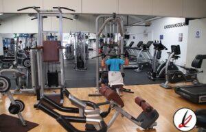 1. Miembro haciendo ejercicio de peso corporal en un gimnasio moderno equipado con máquinas cardiovasculares y de musculación, en Lanzarote Deportes.