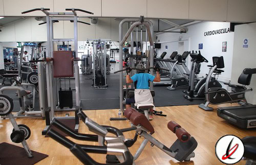1. Miembro haciendo ejercicio de peso corporal en un gimnasio moderno equipado con máquinas cardiovasculares y de musculación, en Lanzarote Deportes.