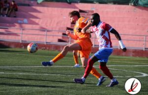 Un jugador de fútbol en acción durante un partido, con un oponente en el campo en Lanzarote Deportivo.