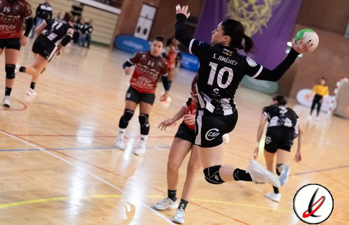 Líder femenino en balonmano en una cancha cubierta durante un partido en Lanzarote. Jugadoras en acción, con una jugadora en primer plano lanzando el balón y otras en defensa y ataque.