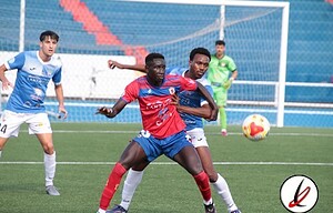 1. Jugadores de fútbol en acción durante un partido en un estadio con grada vacía, mostrando esfuerzo y competencia en el campo deportivo de Lanzarote.