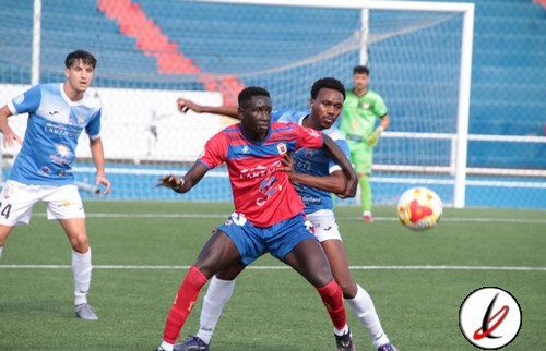 1. Jugadores de fútbol en acción durante un partido en un estadio con grada vacía, mostrando esfuerzo y competencia en el campo deportivo de Lanzarote.