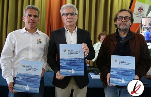 Campeones de la Regata Internacional de San Ginés en Lanzarote con trofeos y certificados, en un evento celebrado en un salón con cortinas verdes y fondo con logos y pantalla digital.