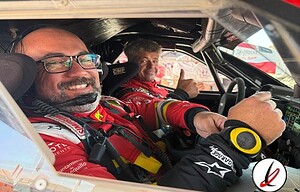 Pilotos de rally en el interior de un coche de carreras durante un evento en Lanzarote, con equipo de protección y sonrisas, listos para competir en una prueba deportiva de alto nivel.