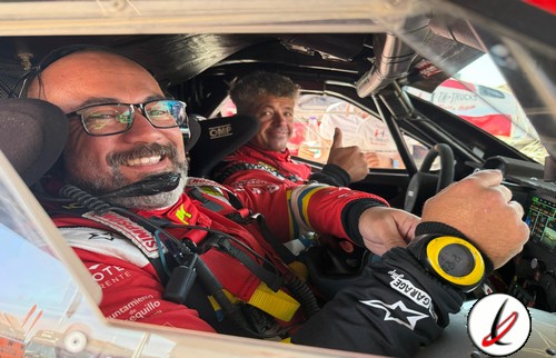 Pilotos de rally en el interior de un coche de carreras durante un evento en Lanzarote, con equipo de protección y sonrisas, listos para competir en una prueba deportiva de alto nivel.