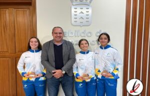 1. Tres deportistas femeninas con medallas y un hombre en una ceremonia en un edificio oficial en Lanzarote.