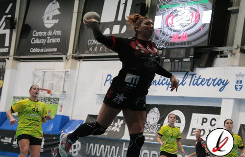 Remaches de remo en acción en un partido de balonmano, jugadores en uniforme en una cancha cubierta con pantallas y anuncios publicitarios en el fondo.